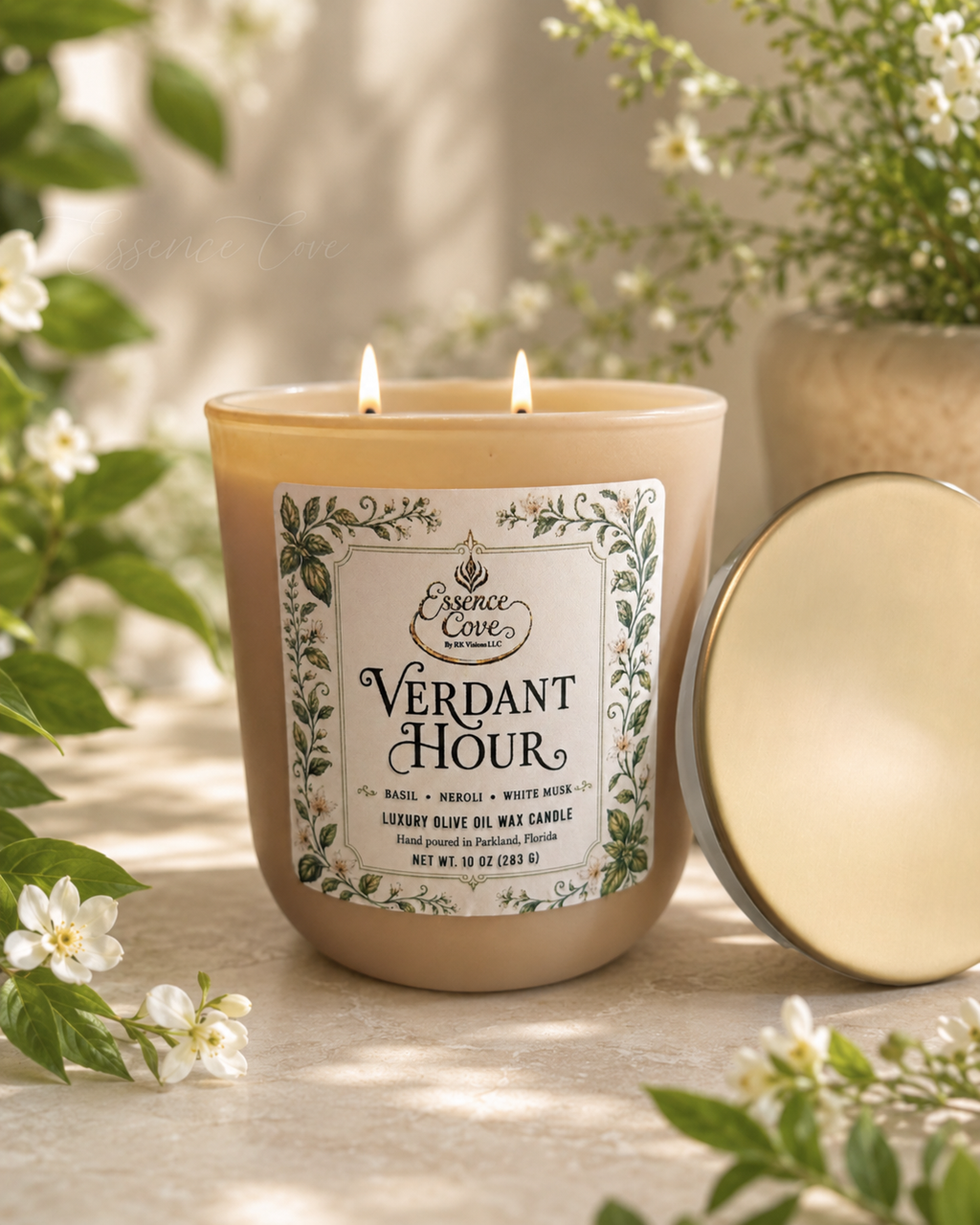 Essence Cove Verdant Hour 10 oz olive oil wax candle with double wick and gold lid surrounded by fresh basil and white flowers.