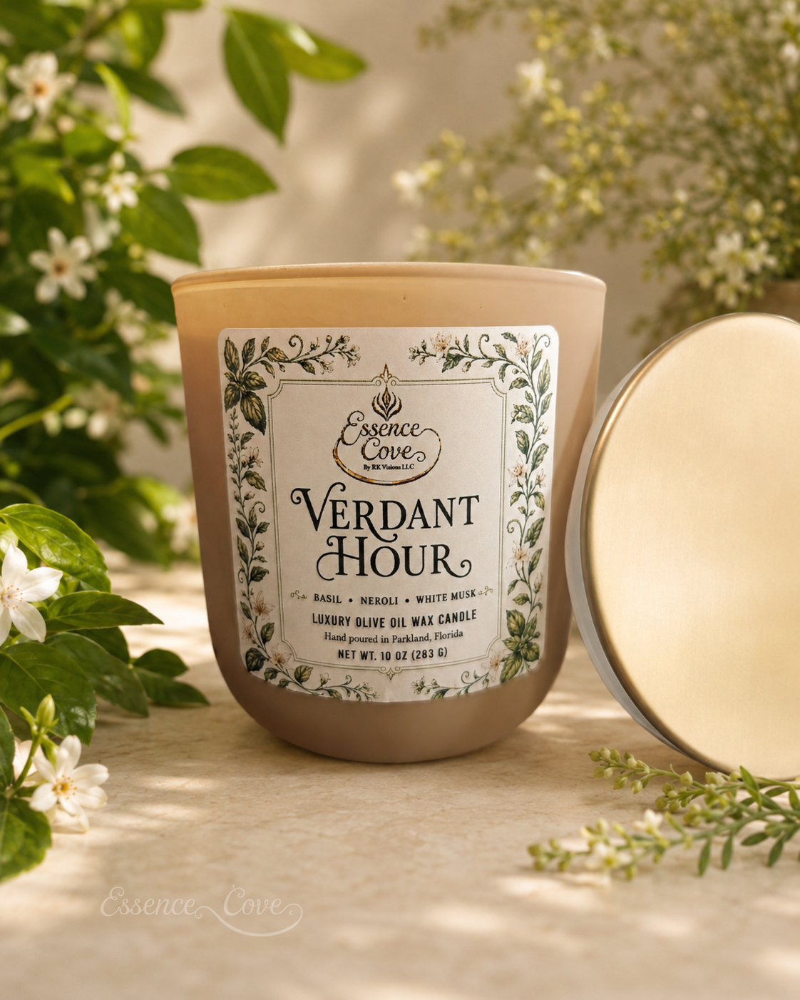 Essence Cove Verdant Hour 10 oz olive oil wax candle with double wick and gold lid surrounded by fresh basil and white flowers.