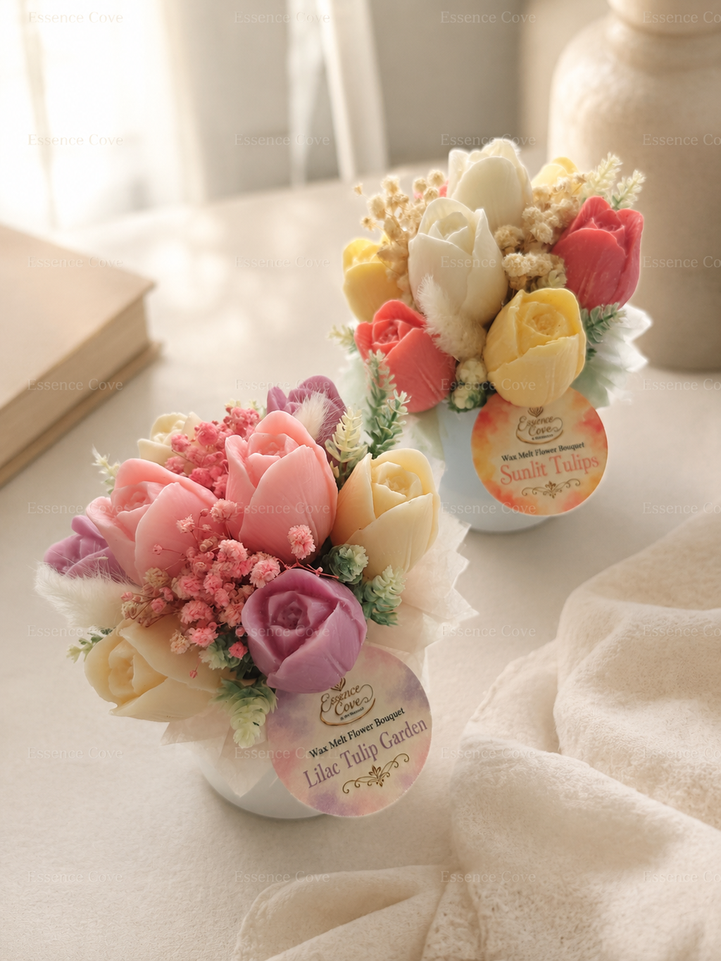 Two handcrafted Wax Flower Tulip Jars by Essence Cove, featuring the colorful Sunlit Tulips arrangement and the pastel Lilac Tulip Garden arrangement in white jars.