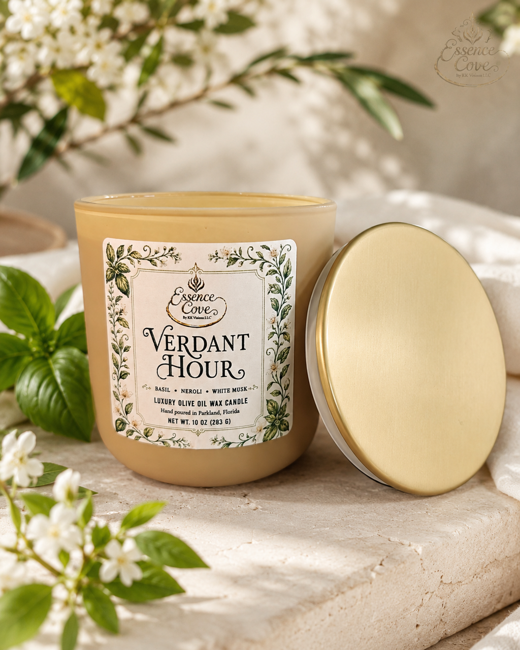 Essence Cove Verdant Hour 10 oz olive oil wax candle with double wick and gold lid surrounded by fresh basil and white flowers.