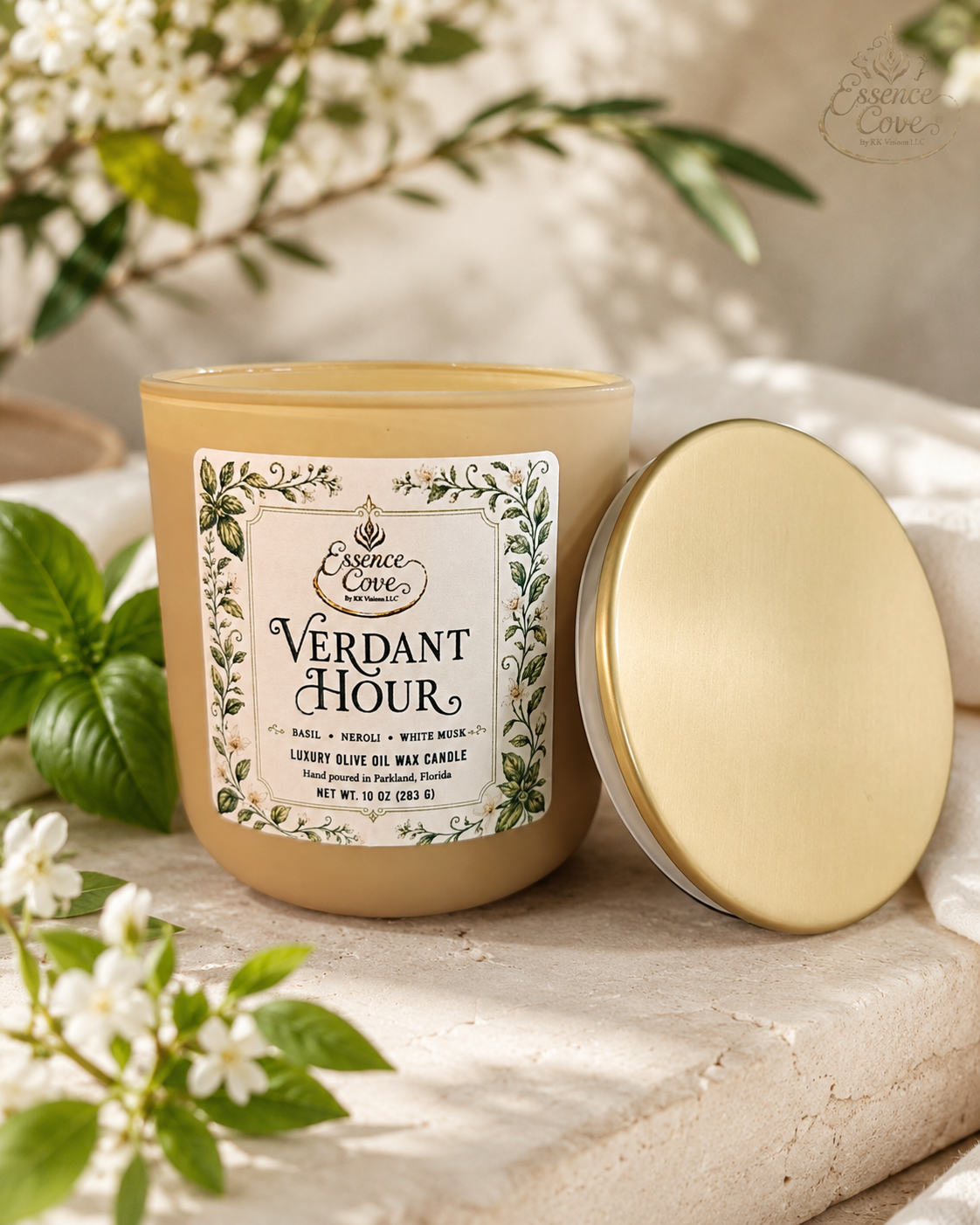 Essence Cove Verdant Hour 10 oz olive oil wax candle with double wick and gold lid surrounded by fresh basil and white flowers.